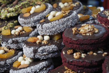 Kalabalık bir pazarda fındık ve meyvelerle süslenmiş çeşitli kurabiyeler..