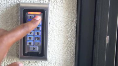 Bir kişi bir binaya girebilmek için şifreyi tuş takımına girer.