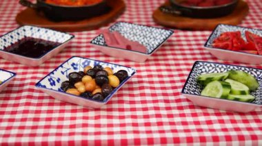 Kırmızı kareli masa örtüsünde çeşitli aperatifler sergileniyor..