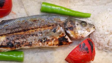 Yanında pirinç ve taze sebzelerle birlikte bir tabak ızgara balığın tadını çıkarın..