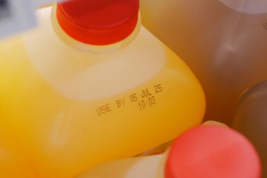 Son kullanma tarihi ve kapaklarını gösteren portakal suyu şişelerinin yakın görüntüsü.