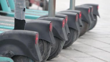 Şehrin kaldırımına park etmiş bir dizi elektrikli scooter. Parlak kırmızı ışıklar..