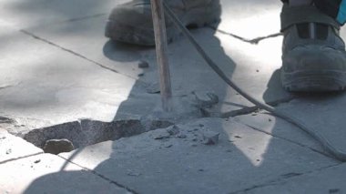 İşçiler güneşli bir günde beton keskiyle hasarlı kaldırımı tamir ediyorlar..