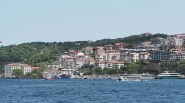 Tekneler, manzaralı evler ve yeşilliklerin yakınındaki sularda süzülüyor..