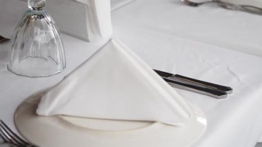 Yemek için beyaz keten ve katlanmış peçeteyle titizlikle hazırlanmış bir masa..