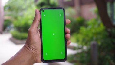 Bir kişi açık yeşil ekranlı akıllı bir telefon sergiliyor..