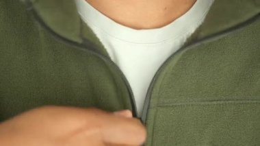 Bir birey fermuarını ayarlar, açık hava kıyafetlerinin detaylarını gösterir..