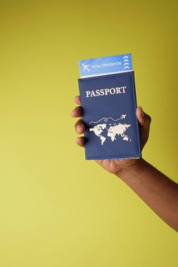 Bir el, sarı üzerinde dünya haritası olan mavi bir pasaport tutar..