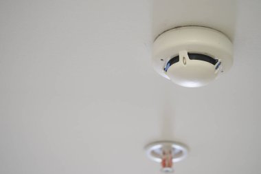 Beyaz bir tavana bir duman dedektörü yerleştiriliyor, içerideki güvenliği sağlıyor..