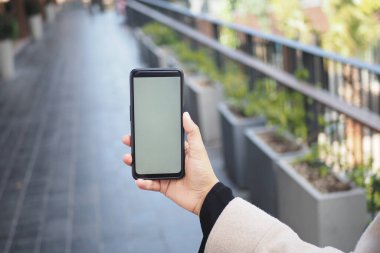 Modern bir yürüyüş yolu boyunca bireysel yürüyüşler, açık havada akıllı telefon tutmalar..