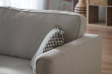 Parlak bir odada desenli yastıklı yumuşak bej bir kanepe..