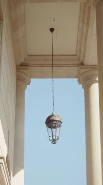 Dekoratif bir fener uzun kolonlar arasındaki tavandan sarkıyor..