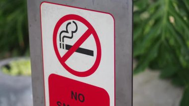 Sigara içilmez tabelası yeşil bir bahçede duruyor, sigarasız bir çevreyi destekliyor..