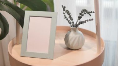 Modern bir tablo, çiçekli ve boş çerçeveli basit bir vazoyu gösterir.