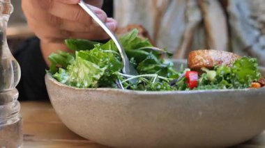 Taze sebzeler ve sebzeler bir kasede ustalıkla karıştırılıyor..