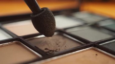 Yakın çekim, farklı gölgelerde fırça kullanarak makyaj uygulamasını gösterir.