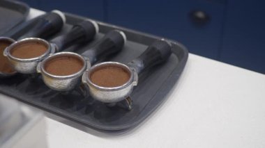 Barista, portatif filtreleri demlenmek için taze kahve telvesiyle dolduruyor..