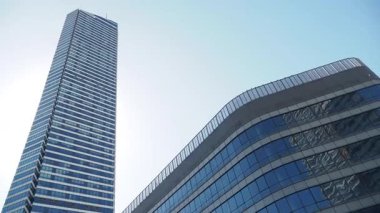 Berrak gökyüzünün altında eşsiz bir modern binanın yanında uzun bir gökdelen duruyor..