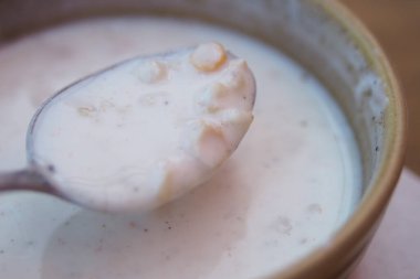 Bir kaşık dolusu kremalı çorba kırsal bir kasede tahıllar barındırır..