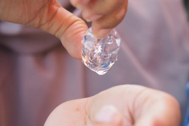 Birisi sıcak bir günde buz küpünü avucunun üzerinde tutar ve damlatır..