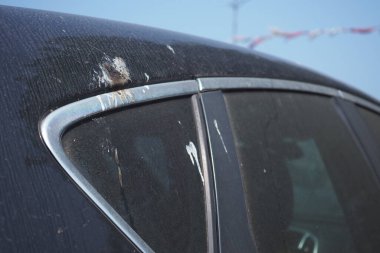 Kirli bir araba açık bir gökyüzünün altında görünür bir kirle park yerinde duruyor..