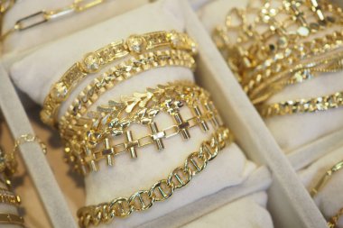 Bir mücevher sergisine yerleştirilmiş çeşitli karmaşık altın bilezikler..