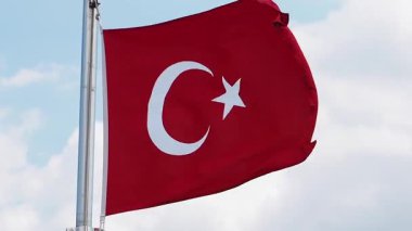 Türk bayrağı açık bir arka planda rüzgarda dalgalanıyor.