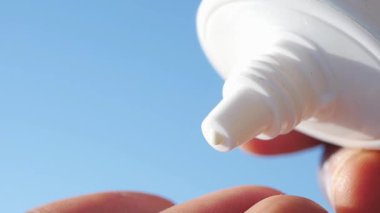 Sahilde eğlenmeye hazırlanırken bir el güneş kremi tutuyor..