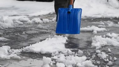 Bir insan bir kürekle kaldırımdan kar temizler, kış görevlerini gösterir..