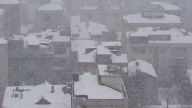 View of rooftops covered in thick snow during a winter storm.