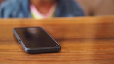 Çocuk eli ile ev masasındaki akıllı telefonu seç.,