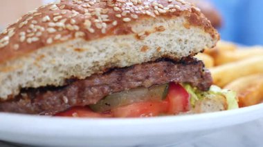 Taze malzemeler ve kızarmış patatesle sulu bir hamburgerin tadını çıkar..