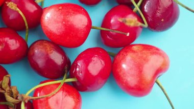Kırmızının çeşitli tonlarında sulu kirazlar mavi arkaplanda yayılıyor..