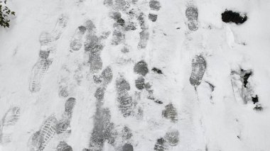 Kış havasında karla kaplı bir yolda görülebilen sayısız ayak izi..