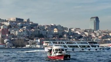 Feribotlar ve küçük tekneler şehrin manzarasıyla birlikte su üzerinde hareket ediyor..