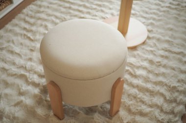 Hafif kumaşlı yumuşak, yuvarlak bir sedir yumuşak bir halıya oturur..