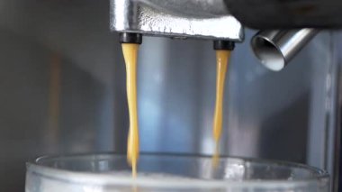 Makineden yavaşça bardağa dökülen zengin kahveyi izle..