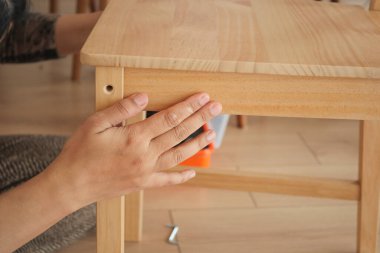 Bir kişi sıcak bir odada ahşap bir masa kuruyor..