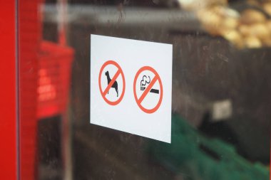 Mağaza girişinde köpek ve sigara içilmeyeceğini gösteren işaretler var..
