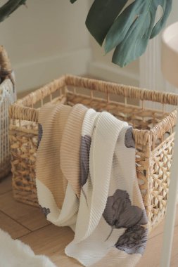 Yumuşak bir battaniye, parlak bir odada örülmüş bir sepetin üzerine öylesine asılır..