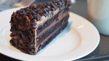 Indulge in a slice of rich chocolate layer cake topped with chocolate curls.