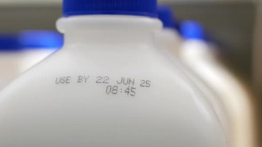 Milk bottles are arranged in a row displaying their expiration dates clearly.