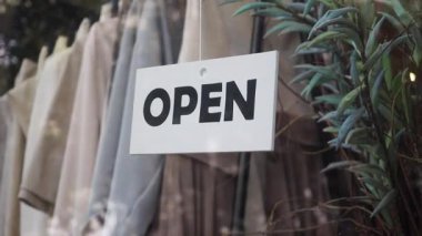 Bir karşılama tabelası elbise mağazasının bugün müşteriler için açık olduğunu gösteriyor..
