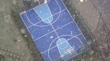 Kar, kar yağarken boş bir basketbol sahasını örtüyor.