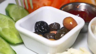Canlı bir tabakta taze zeytin, salatalık ve domateslerin tadını çıkarıyorlar..