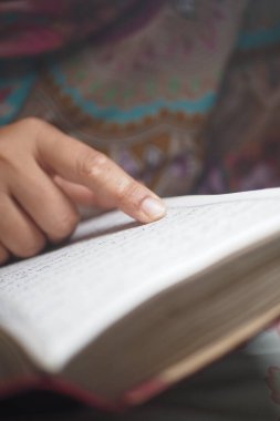 Metni işaret ederken Kuran okuyan kişi.