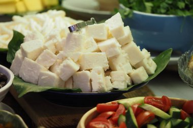 Yanında sebzeler ve tabakta sergilenen taze peynir küpleri..