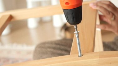 Konforlu bir alanda elektrikli matkap kullanarak ahşap mobilyalar monte etmek.