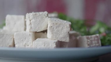 Taze tofu parçaları düzgünce bir tabakta yeşilliklerin yanına dizilir..