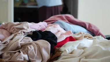 Bir insan sıcak bir odada büyük bir çamaşır yığını organize eder..